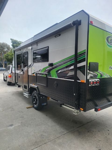 Ausflex Fierce 18.6 in green and black, side view with the awning arm folded along the wall