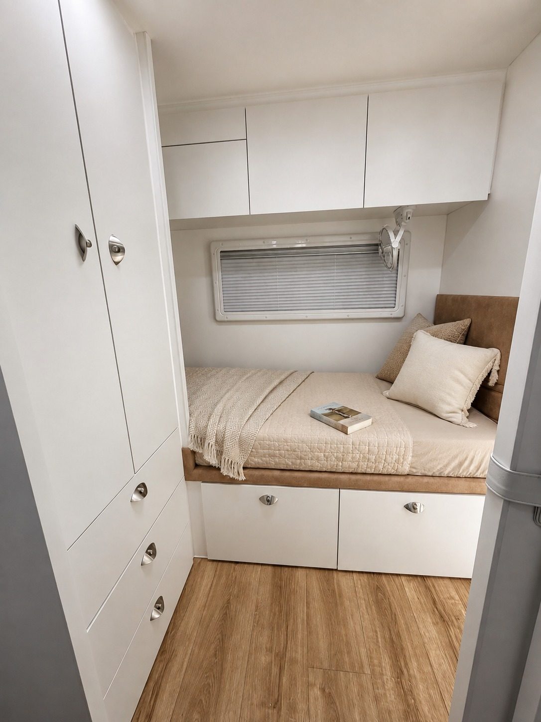 Single bunk made up in cream linen with overhead lockers and timber floor