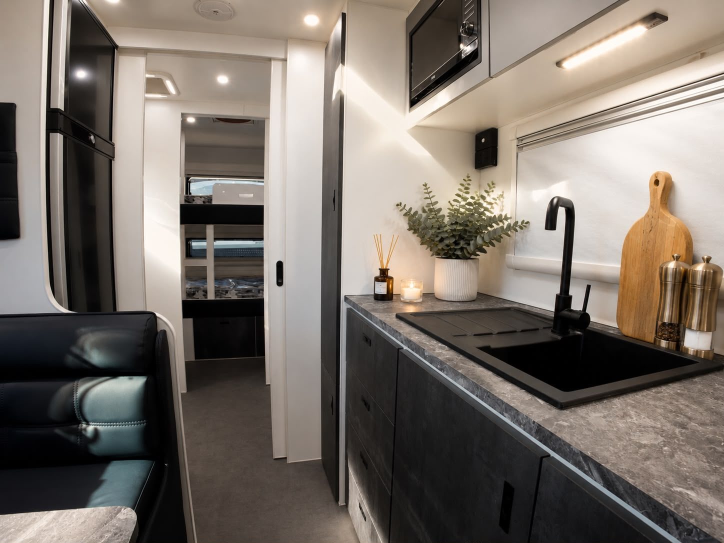 Kitchen with stone benchtop and black sink, bunks visible down the hallway